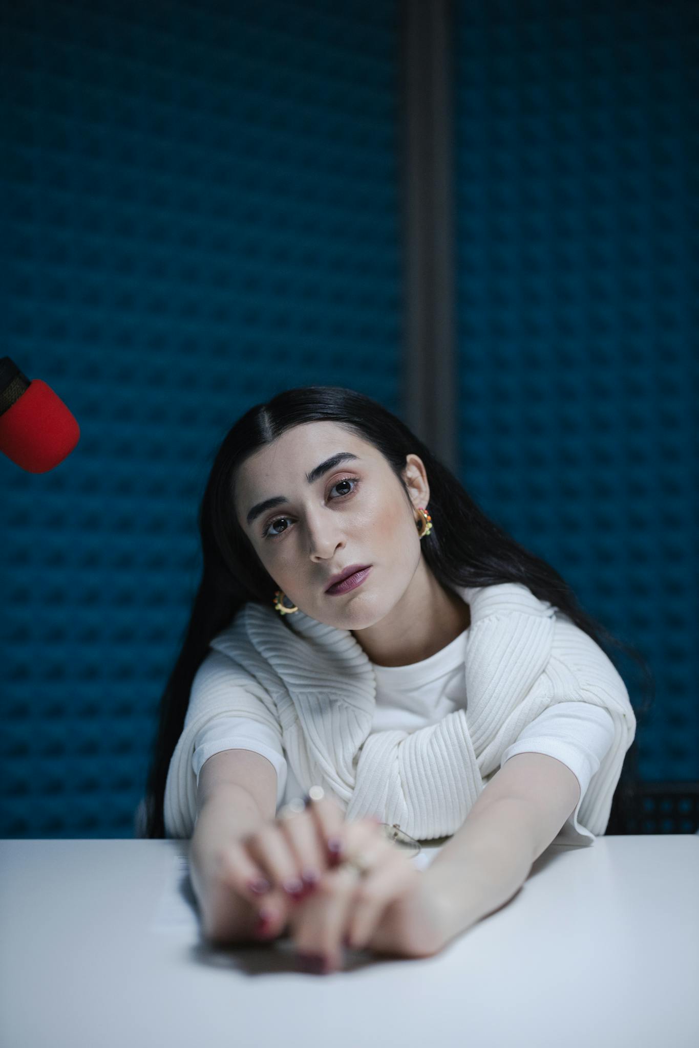 Woman posing in a recording studio with microphone, looking thoughtfully at camera.